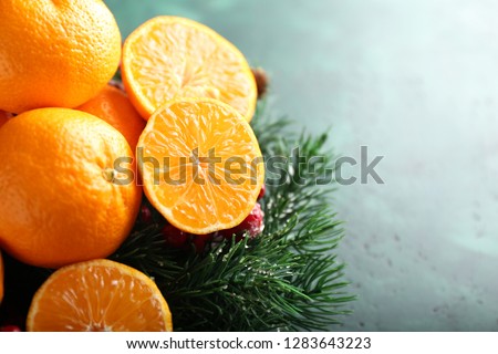Christmas wreath with tasty tangerines on color background, closeup