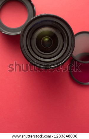 Professional photography lenses and accesories over red background with copy space.