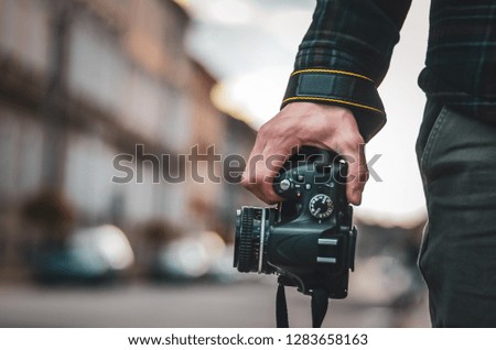 Photographer holding camera in hand during journey. Man hipster with retro photo camera Fashion Travel Lifestyle outdoor foggy nature on city street background