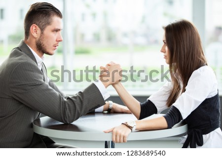 business and office concept - businesswoman and businessman arm wrestling during meeting in office