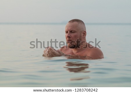 Emotional bald man posing in the surf in the water on the beach