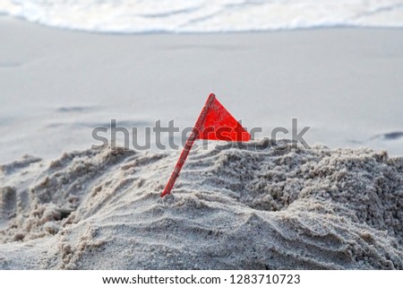 Closeup Red flag on the white sand  and the beach                  