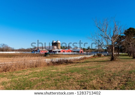 Wide-angle shot of a red barn, silos, a stable and fencing on a farm in rural Virginia.