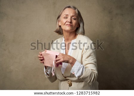 Smiling elderly woman holding a pink packet