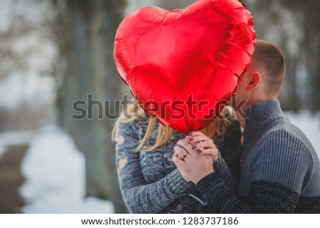 couple hidden by the big red heart-shaped balloon