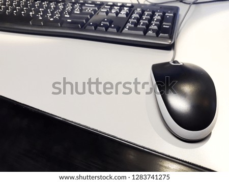 The mouse and black keyboard are placed on a white table.