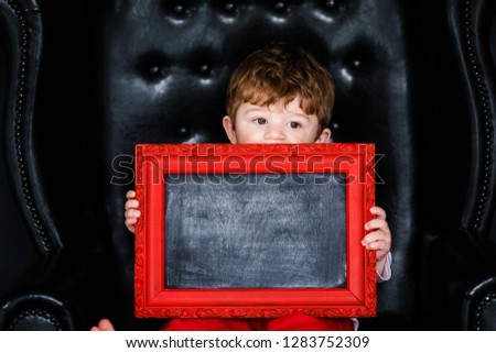 Little boy sitting on the armchair with red framed picture on the St. Valentine's day. little feet close-up.