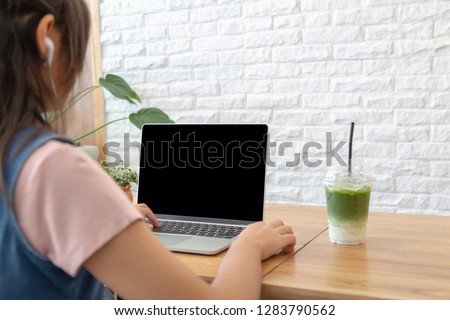Teenage use laptop on wood table, her work or study in cafe. The blank screen with copy space for your text or advertising content and clipping path on picture. 
