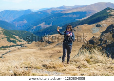 smiling woman in sunglasses making selfie in mountains