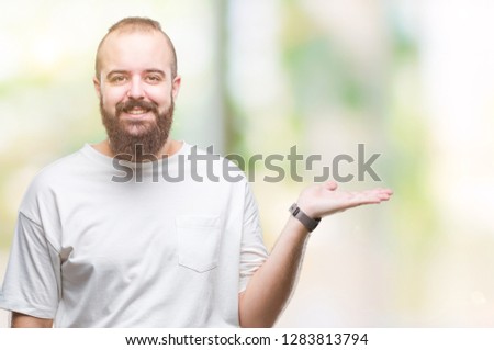 Young caucasian hipster man wearing casual t-shirt over isolated background smiling cheerful presenting and pointing with palm of hand looking at the camera.