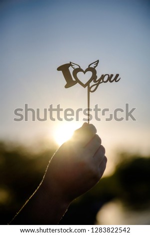 Girl holding the inscription I love you, on the sunset background