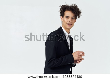 Funny cute man in a black suit with curly hair on a gray background