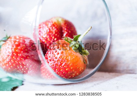 Strawberries in a glass on a wooden floor