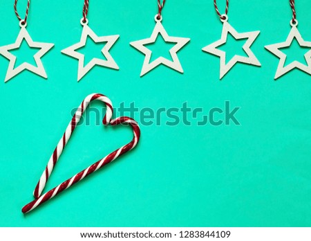 Caramel heart and white stars on green pastel trendy background. Festive backdrop for package and projects. Flat lay, close up. Top view, copy space.