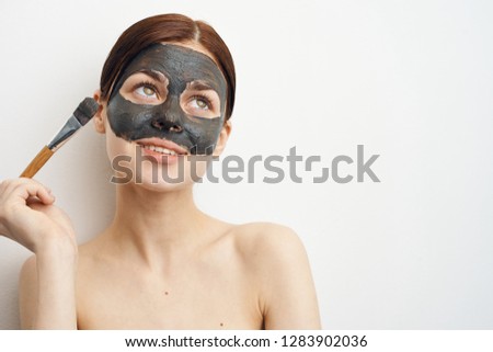 woman applies clay mask on face