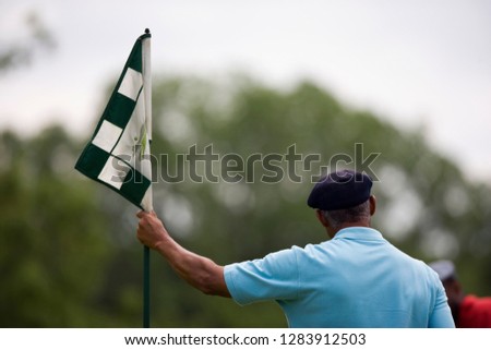 Man standing with flag on golf course