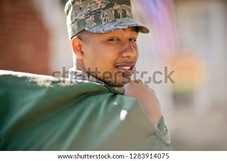 Portrait of a smiling soldier carrying a bag over his shoulder.