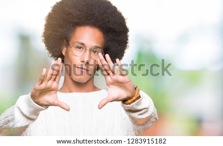 Young african american man with afro hair wearing glasses Smiling doing frame using hands palms and fingers, camera perspective