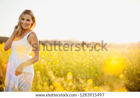 Portrait of woman in a white dress standing in a meadow.