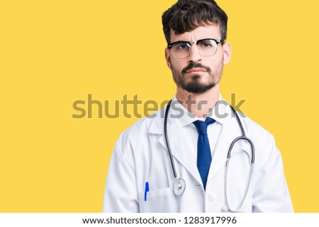 Young doctor man wearing hospital coat over isolated background skeptic and nervous, frowning upset because of problem. Negative person.