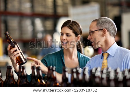 Two colleagues examining a row of beer bottles.