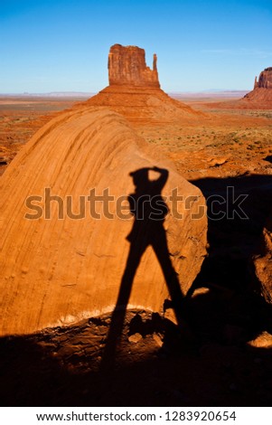 Shadow of a photographer against an eroded rock formation in a rural landscape.