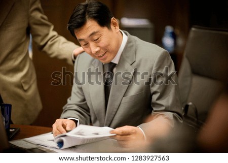 Mid-adult businessman having a meeting with colleagues in a boardroom.