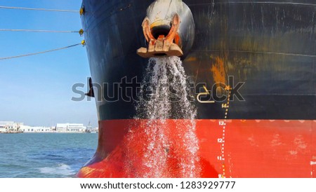 Large cargo ship discharging ballast water out from the Anchor's hub Royalty-Free Stock Photo #1283929777