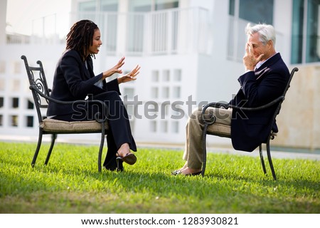Mid-adult businessman speaking with a male colleague outside.