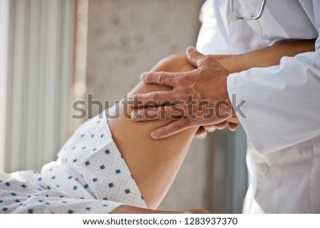 Doctor's hands examining a patient's knee.