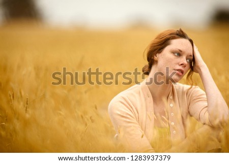 Pensive teenage girl in wheat field.