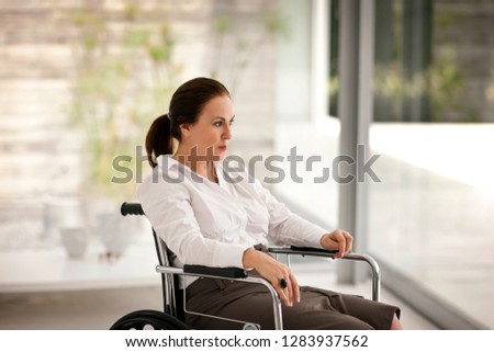 Portrait of senior woman in a wheelchair looking outside.