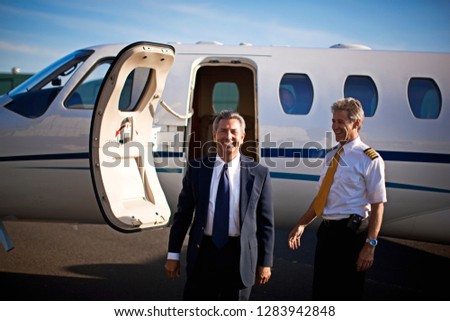 Businessman and a pilot standing in front of a private jet