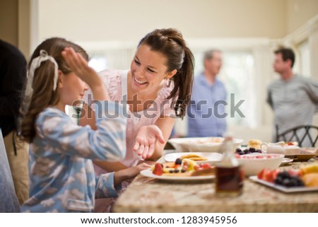 Young woman and girl high fiving after making breakfast together