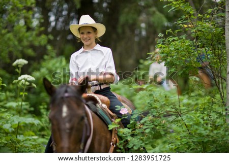 Girl riding horse through forest