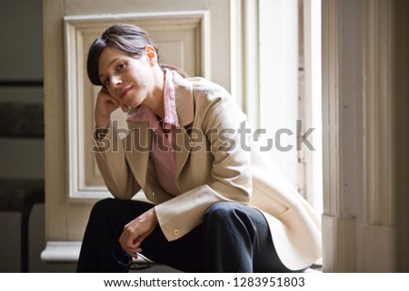 Portrait of a mid-adult woman sitting with her head resting on her hand.
