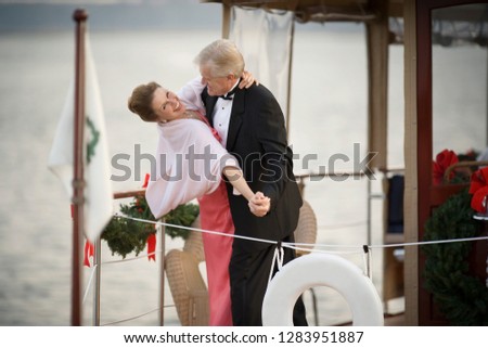Portrait of a mature adult couple dressed formally and dancing on a boat.