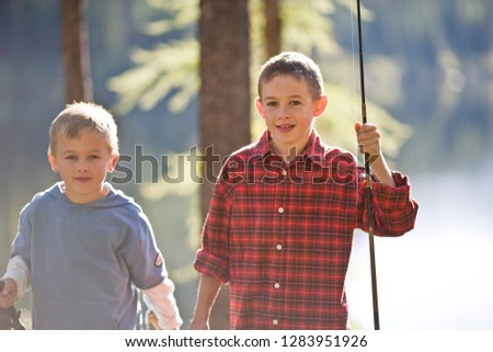 Portrait of two young brothers holding fishing rods while out in the forest.