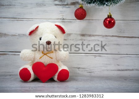 Teddy bear holding a heart-shaped pillow with plank wood board background 