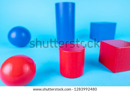 Blue and red geometric shapes on blue background. Abstract construction from wooden blocks. The concept of creative, logical thinking. Different wooden shapes.