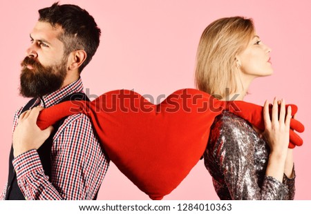 Boyfriend and girlfriend have break. Relationship and valentines day concept. Couple in love tears big heart on pink background. Girl and bearded man with grumpy faces divide soft toy heart with hands