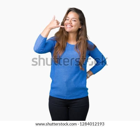 Young beautiful brunette woman wearing blue sweater over isolated background smiling doing phone gesture with hand and fingers like talking on the telephone. Communicating concepts.