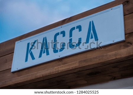 A sign of the ticket office in Russia. Purchase tickets for entertainment. Inscription in Russia means Cash Desk. Blue letters on wooden background.