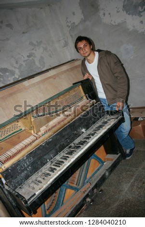 10.19.2008, Moscow, Russia. A young man standing behind an old piano. An old destroyed musical instrument close up. 