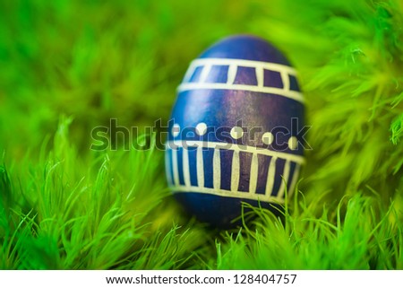 Handcrafted decorative easter egg on grass background;