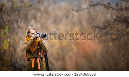 Pretty, female photographer taking pictures outdoor on a lovely autumn day - shallow DOF, color toned image