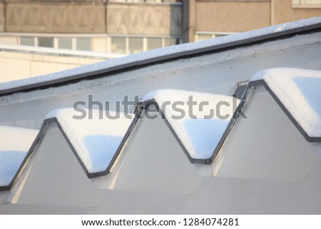 snow caps on the roof of the building, figured roof, geometry of the building. winter Sunny weather