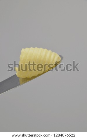 Delicious roll of butter on a knife blade. Butter is used for cooking and baking and it adds a tasty flavor to the food. Picture is ideal for advertising dairy products,