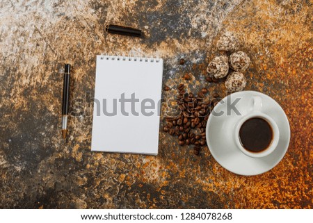 White cup with black coffee on a gray stone background and a blank sheet of paper. Place for text.