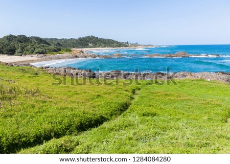 Beach coves with blue ocean wave waters to horizon with rocky coastline and green vegetation landscape